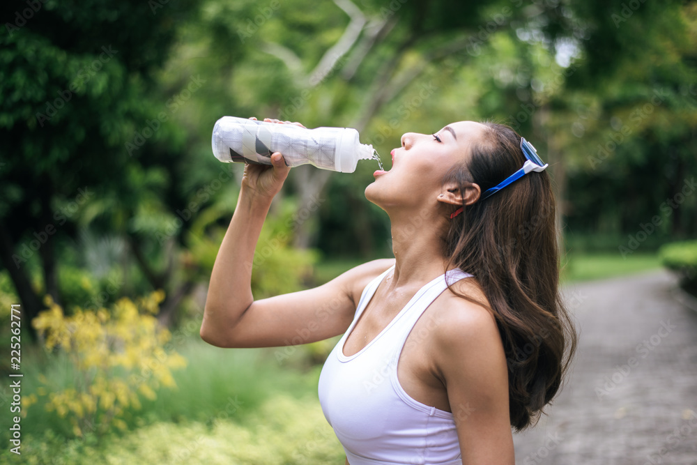 Young healthy woman drinking water from plastic bottles after jogging. Health and sport concept. Young healthy woman drinking water from plastic bottles after jogging. Health and sport concept.