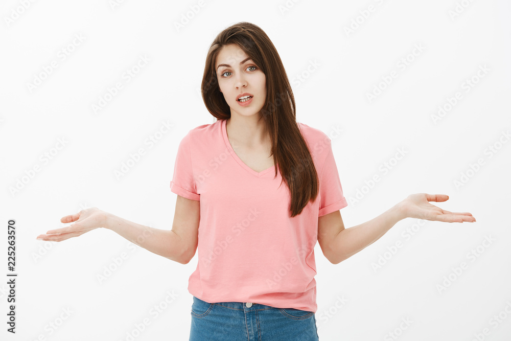 Portrait of unaware questioned attractive female coworker in pink t-shirt, shrugging and spreading hands in both sides in clueless gesture, being confused and having no idea what she was blamed for Portrait of unaware questioned attractive female coworker in pink t-shirt, shrugging and spreading hands in both sides in clueless gesture, being confused and having no idea what she was blamed for