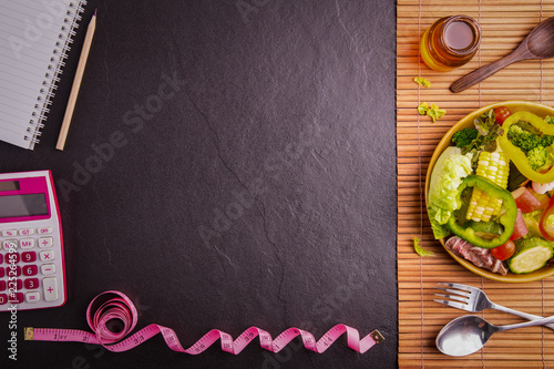 Diet plan, tape measure, calculator for Count calories,  .salad healthy food on wood and black stone background.Weight loss. Copy space.