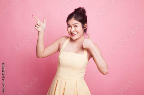 Young Asian woman point and thumbs up.