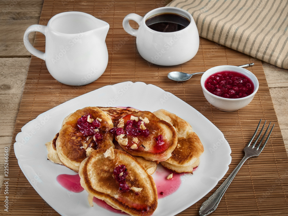 Pancakes stuffed with jam and sprinkled with walnuts lie on a white plate Pancakes stuffed with jam and sprinkled with walnuts lie on a white plate
