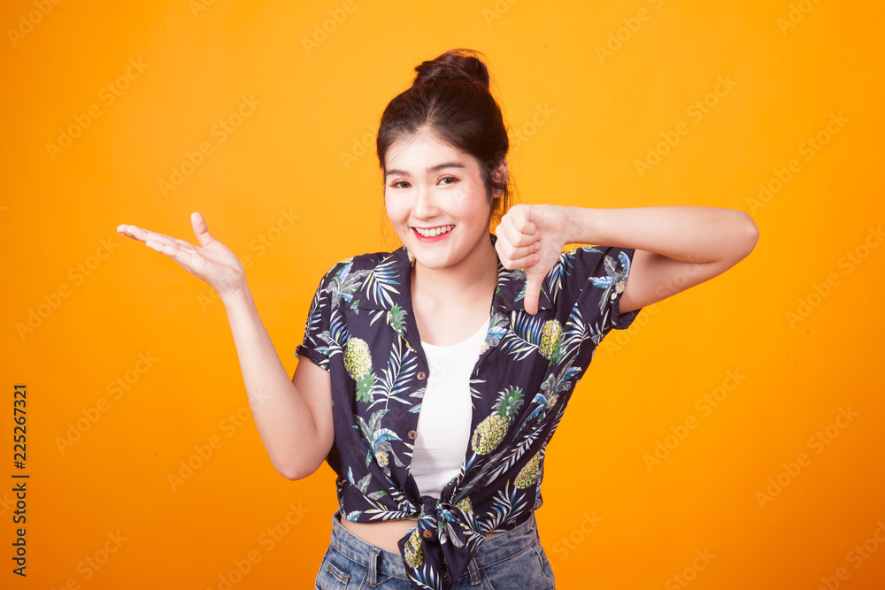 Young Asian woman show palm hand and thumbs down in tropical shirt Young Asian woman show palm hand and thumbs down in tropical shirt