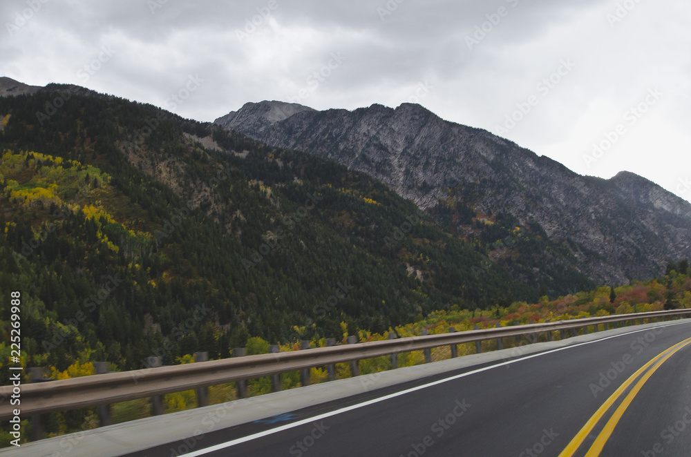 A long wet road running along side the granite mountain range in utah. 