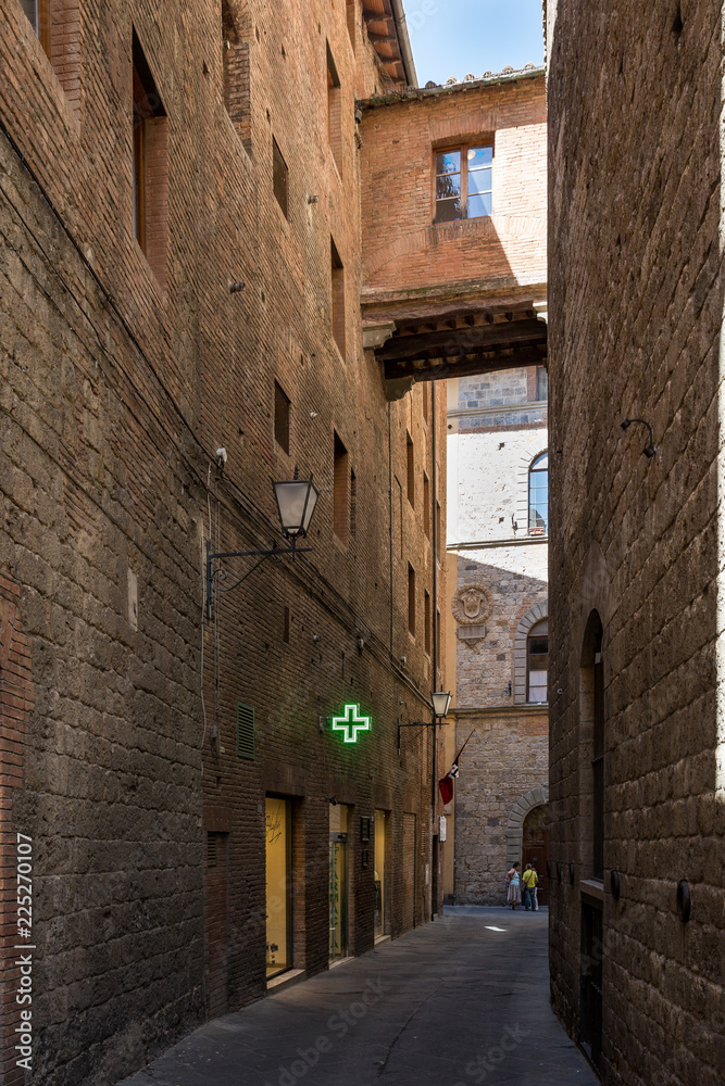 Pharmacy sign in a side street in Siena Italy