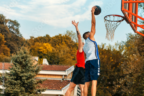 Two young friends playing basketball on court outdoors during the day. © Zoran Zeremski