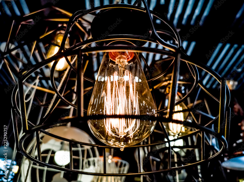 Tungsten orange light bulb hanging on the inside of the building with a black iron fence around,Lighting in buildings with multi-colored electric lamps,soft focus.
