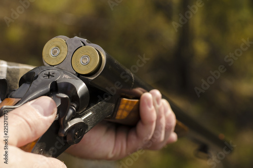 The twelve-gauge two-barrelled loaded coachgun in man's hands photo