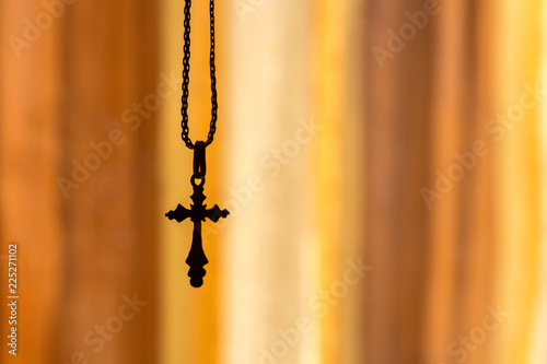 a cross on a chain on an orange background