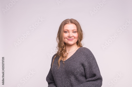 Fashion, style and people concept - portrait of a beautiful young woman with a tender smile she looks at the camera over white background with copy space