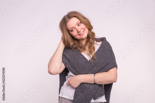 Beautiful young woman with hand in curly hair wearing cardigan on white background