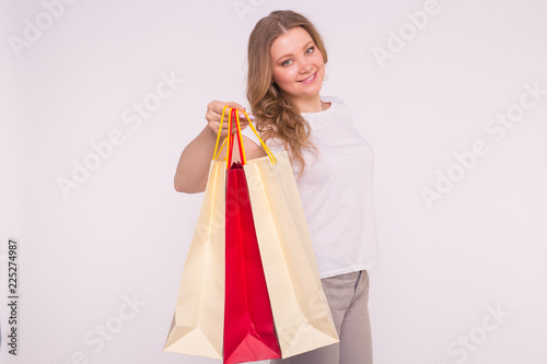 Smiling blonde woman with shopping bags on white background