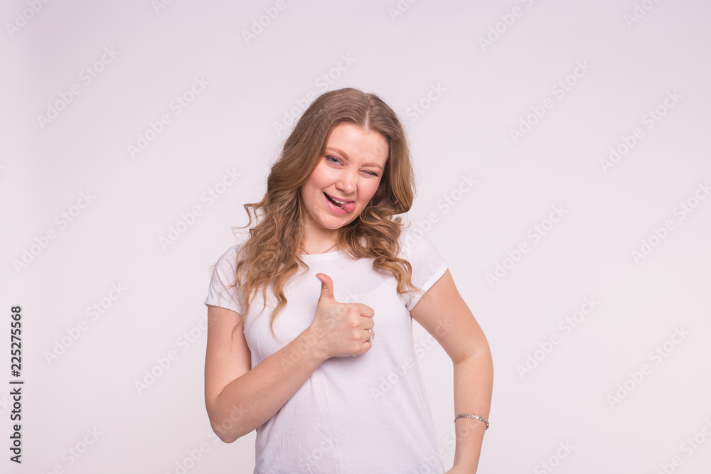 Fashion, style and gesture concept - winking pretty woman over white background showing thumbs up Fashion, style and gesture concept - winking pretty woman over white background showing thumbs up