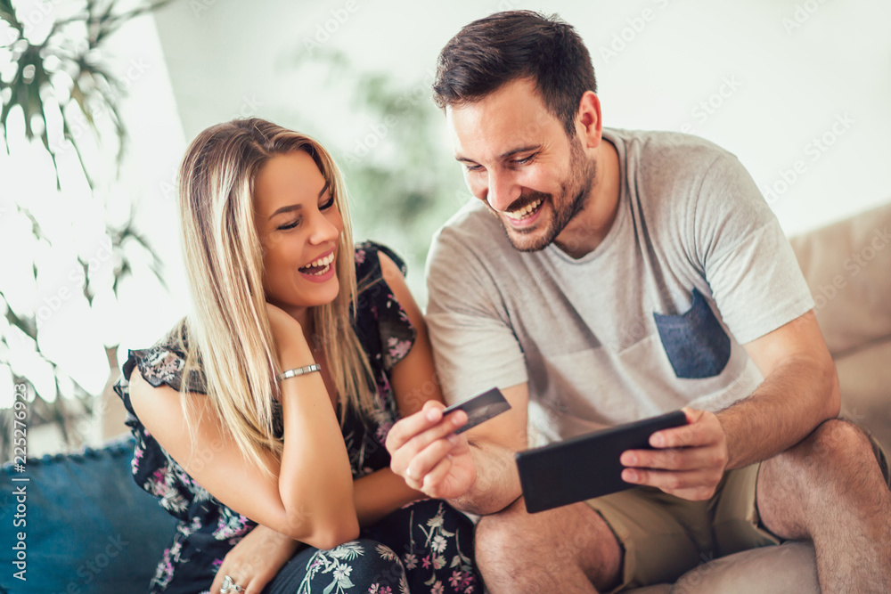 Smiling happy couple couple with tablet pc computer and credit card at home-technology, online shopping and people concept Smiling happy couple couple with tablet pc computer and credit card at home-technology, online shopping and people concept