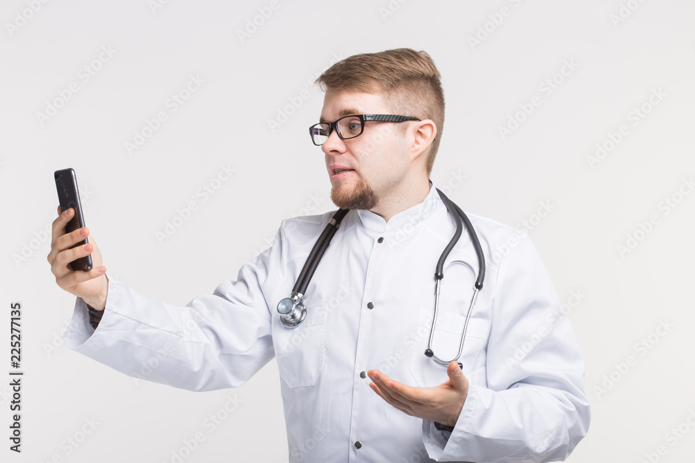 Happy male doctor making selfie photo with smartphone on white background Happy male doctor making selfie photo with smartphone on white background