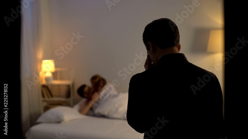 Shocked male catching his wife with her lover making love in bed, adultery