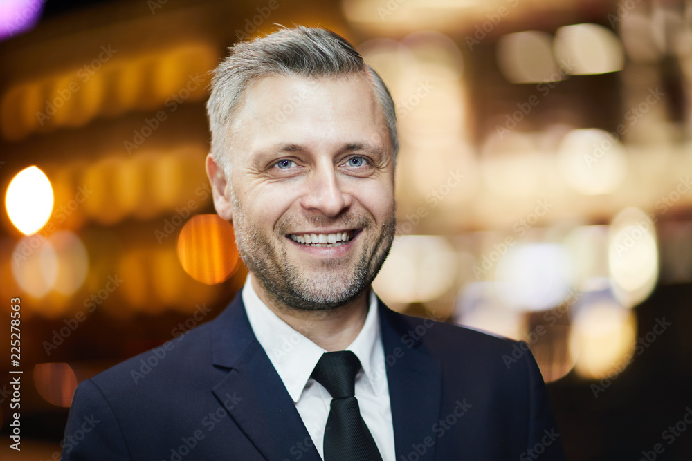 Cheerful man in elegant suit and tie enjoying walk in urban environment aith night lights Cheerful man in elegant suit and tie enjoying walk in urban environment aith night lights
