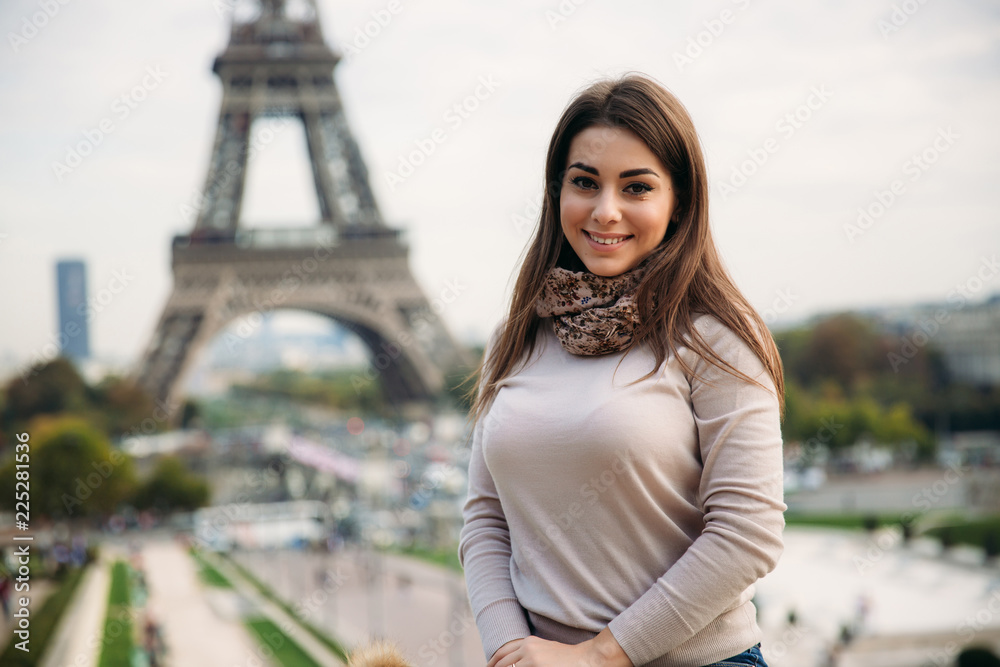 Beautiful lady sist on border against of eiffel tower. Lady smile and have fun