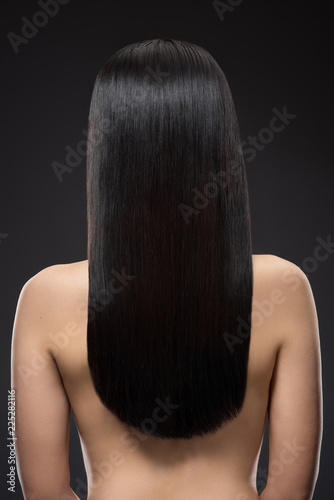 back view of woman with beautiful shiny hair isolated on black