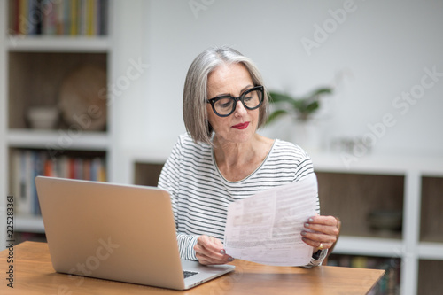 Mature adult female paying bill online using a laptop photo