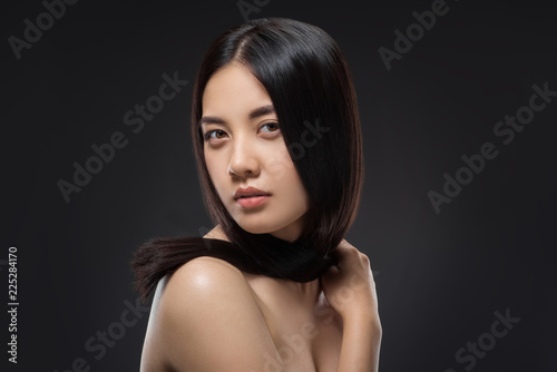 portrait of young asian woman with beautiful and healthy dark hair posing isolated on black