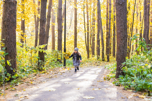 Fall, childhood, people concept - little happy girl walking in autumn park