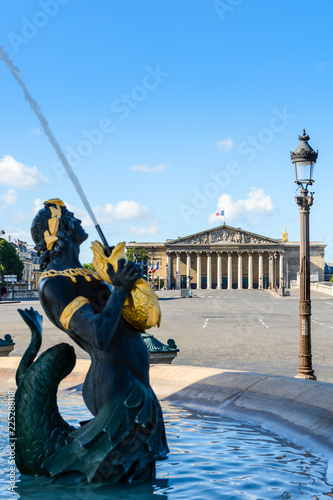 The french National Assembly seen from the Concorde square in Paris, France, with the Fountain of the Seas in the foreground, whose Nereids and Tritons hold golden fishes spitting water upwards. photo