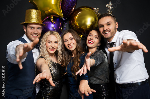 celebration, people and holidays concept - happy friends at christmas or new year party with balloons over black background