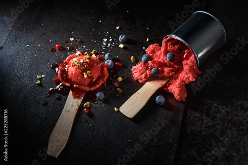 Two scoops of red gelato served on paint stirrers and paint can