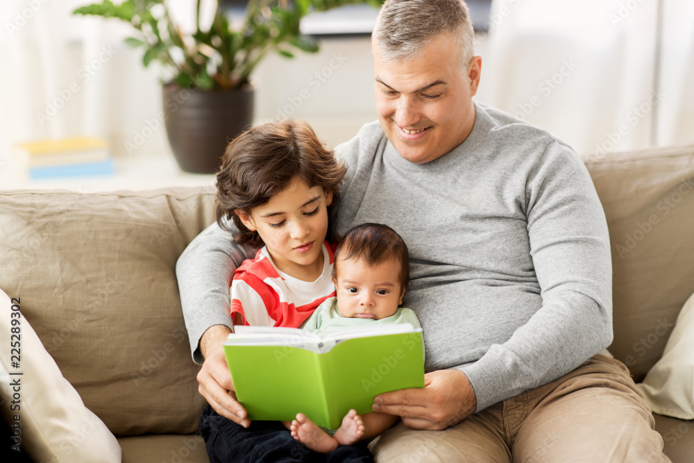 family, fatherhood and people concept - happy father with preteen and baby son reading book at home