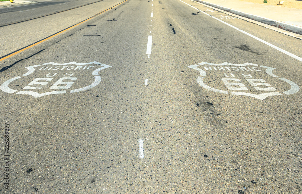 Fototapeta premium Pavement street sign on historic route 66 in Barstow, Mojave desert. Mother Road or Sixty Six background. Route 66 highway with sign on asphalt.