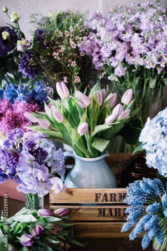 Fototapeta Naklejka Na Ścianę i Meble -  Beautiful fresh blossoming flowers (hydrangea, tulips, muskari) in blue and purple colors standing in a wooden rustic box at the florist shop