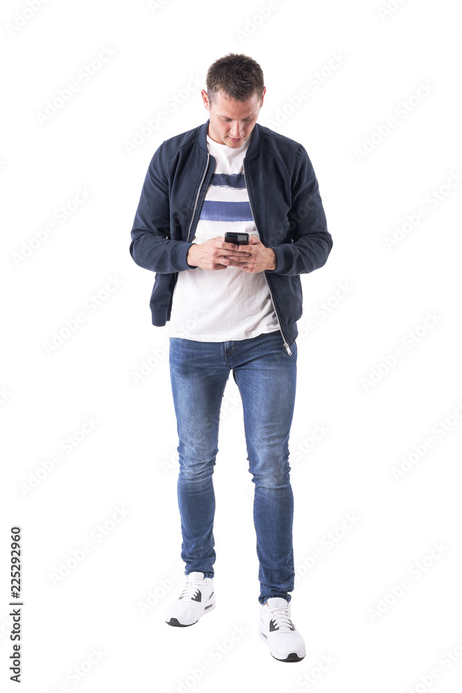 Front view of young adult casual man using and looking down at mobile phone. Full body isolated on white background. 