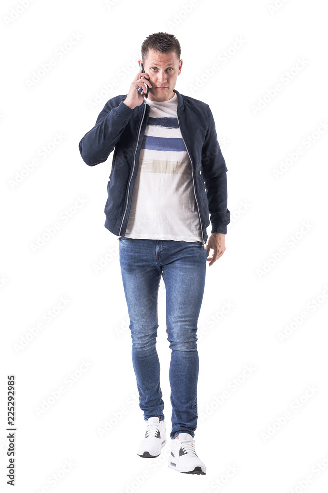 Angry upset adult man talking on the phone looking at camera walking and approaching. Full body isolated on white background. Angry upset adult man talking on the phone looking at camera walking and approaching. Full body isolated on white background.
