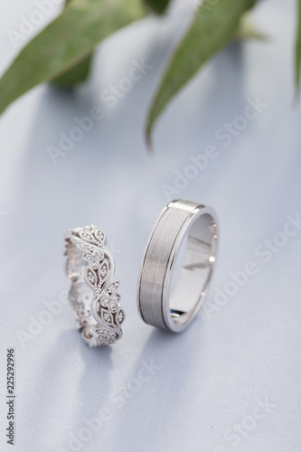 Pair of silver wedding rings with diamonds on blue background