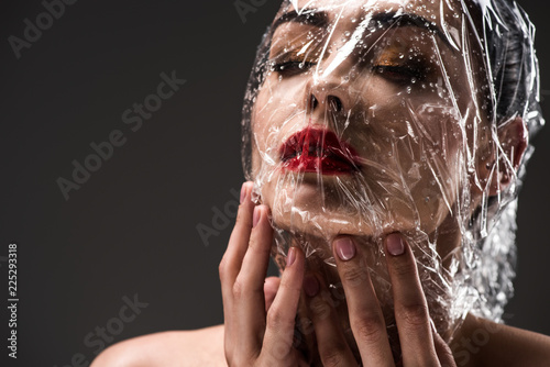 Billede på lærred sensual young woman with face wrapped in wet transparent cellophane isolated on