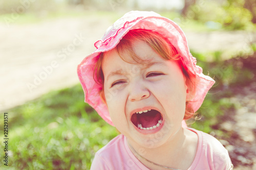 Portrait of an unhappy child. Baby screams. The child is angry