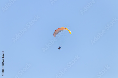 Paraglider flying with a paramotor over clear blue sky