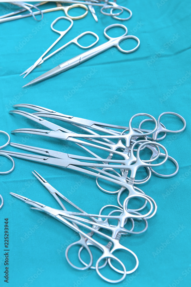 Detail shot of steralized surgery instruments with a hand grabbing a tool take with art lighting and blue filter Detail shot of steralized surgery instruments with a hand grabbing a tool take with art lighting and blue filter