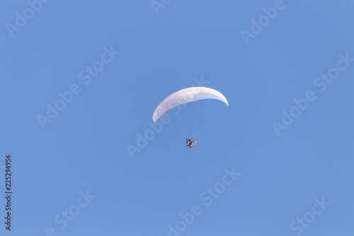 Paraglider flying with a paramotor over clear blue sky