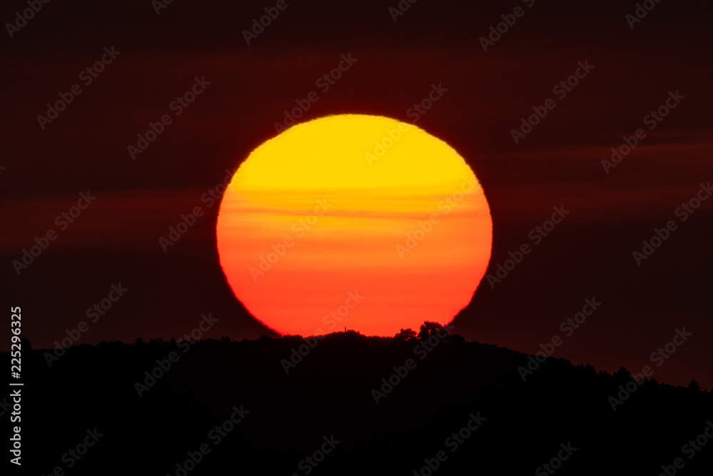 Sunrise over mountain peak with huge orange sun on top