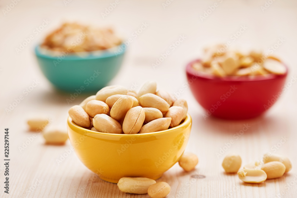 Peanuts bowls on a wooden background. Vegetarian snacks in a colorful bowls. Selective focus. Peanuts bowls on a wooden background. Vegetarian snacks in a colorful bowls. Selective focus.