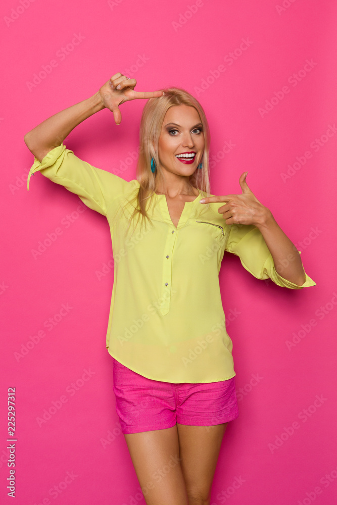 Beautiful Blond Woman In Vibrant Clothes Is Showing Frame Hand Sign Beautiful Blond Woman In Vibrant Clothes Is Showing Frame Hand Sign
