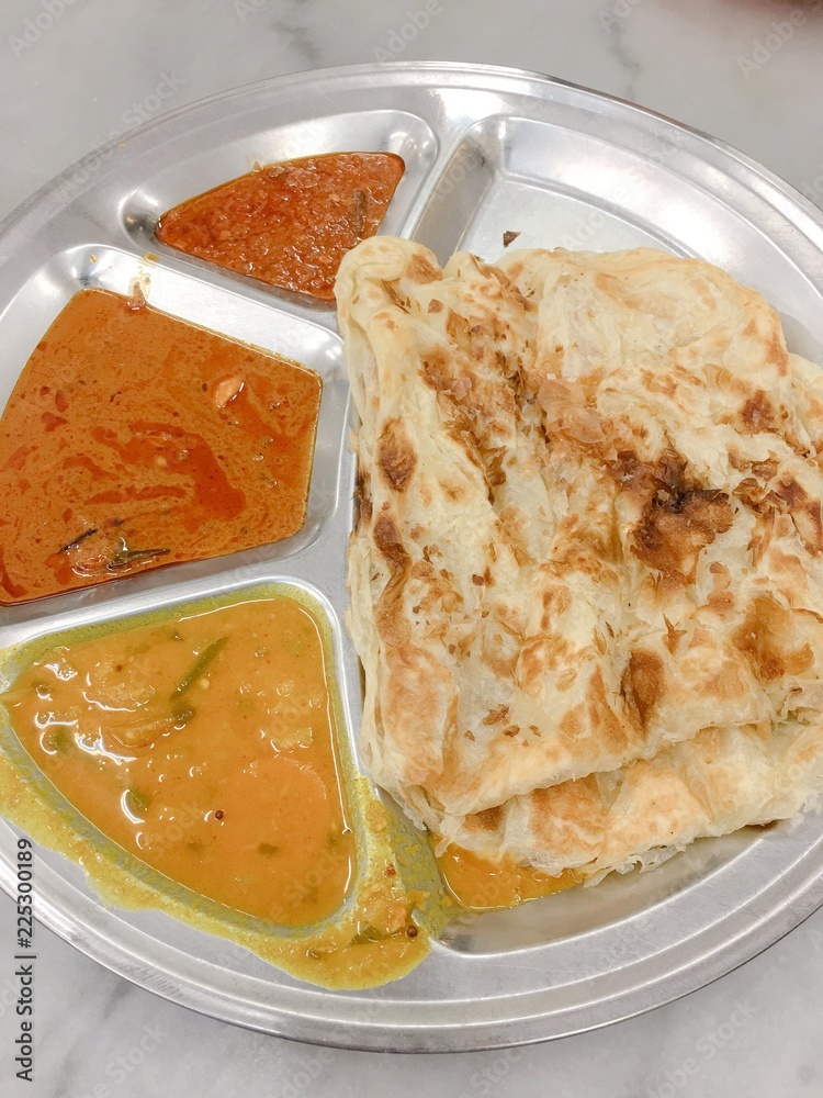 Roti canai, served with dal and curry. It is also known as roti cane or