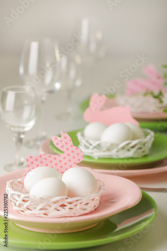 Happy easter. Decor and table setting of the Easter table - Branches of flowering spring tree, dishes of pink and green color.