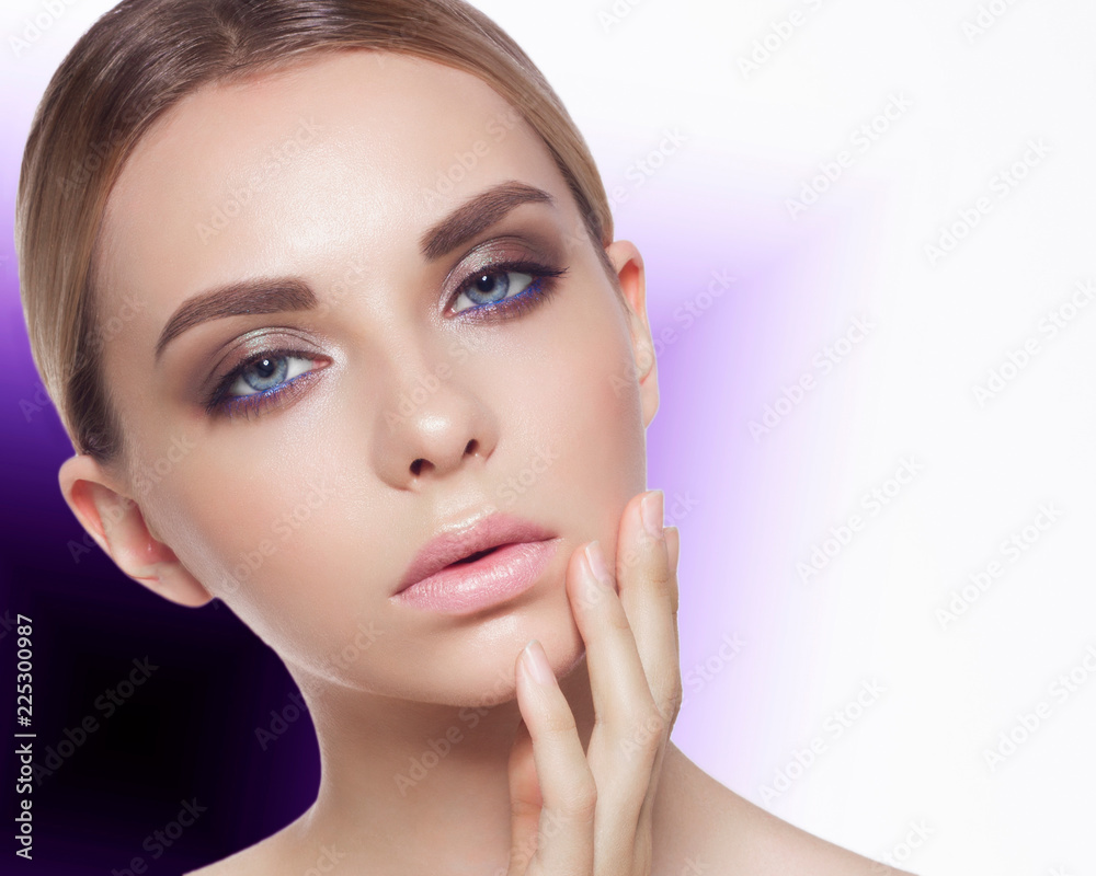 On a bright unusual background a portrait of the young woman, showing care of face skin. Fashionable make-up and chubby pink lips. Spa, cosmetology and beauty shop