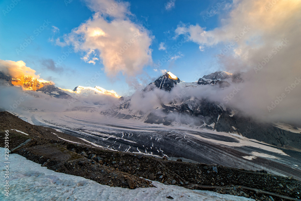 Obraz premium Dramatic sunset scene in high mountains. Clouds covering high peaks of Valais Alps (Pennine Alps), Switzerland in a evening light.