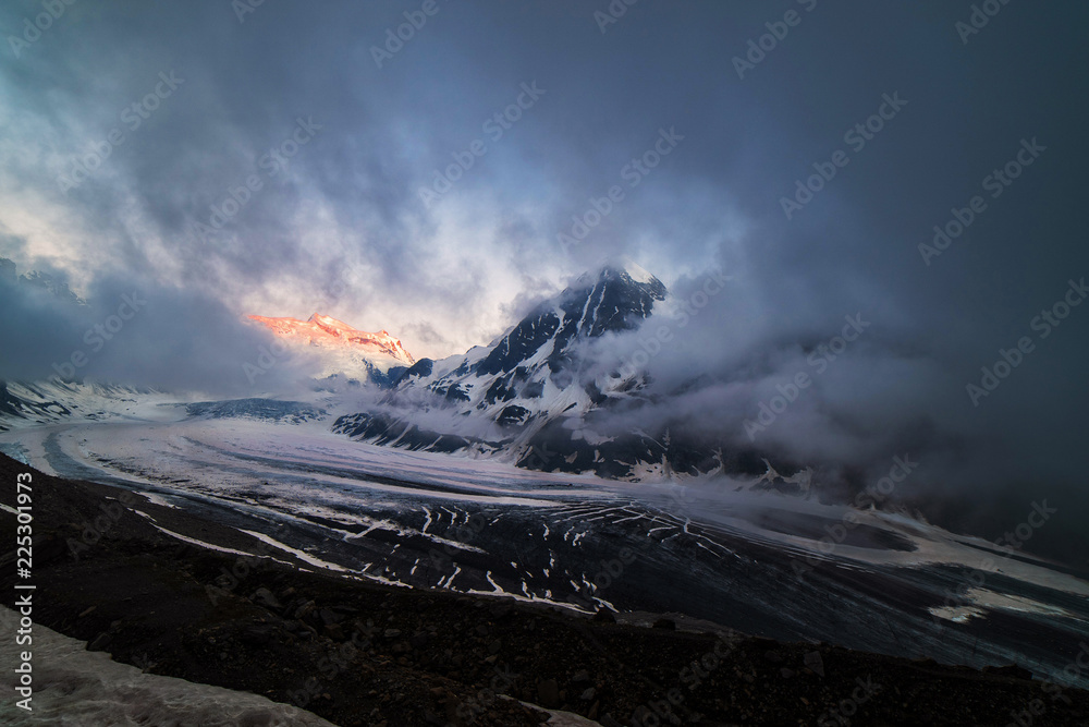 Obraz premium Dramatic sunset scene in high mountains. Clouds covering high peaks of Valais Alps (Pennine Alps), Switzerland in a evening light.