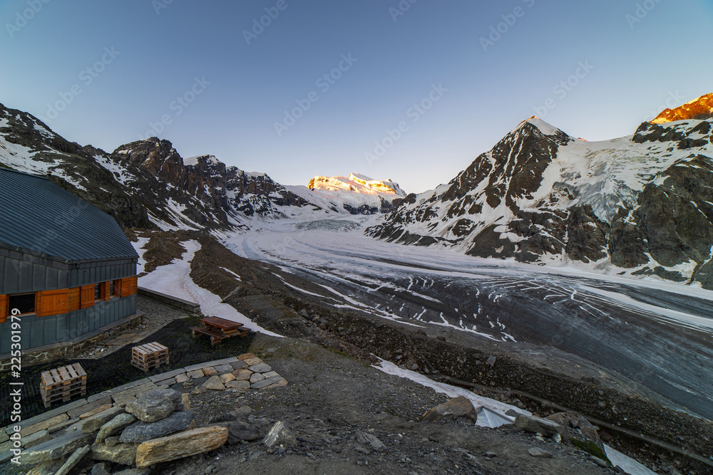 Fototapeta premium Scenic view of beautiful landscape of Swiss Alps with a majestic Glacier de Corbassiere in a view, Switzerland. Clear sky sunrise in Valais Alps (Pennine Alps), Switzerland in a early morning light.