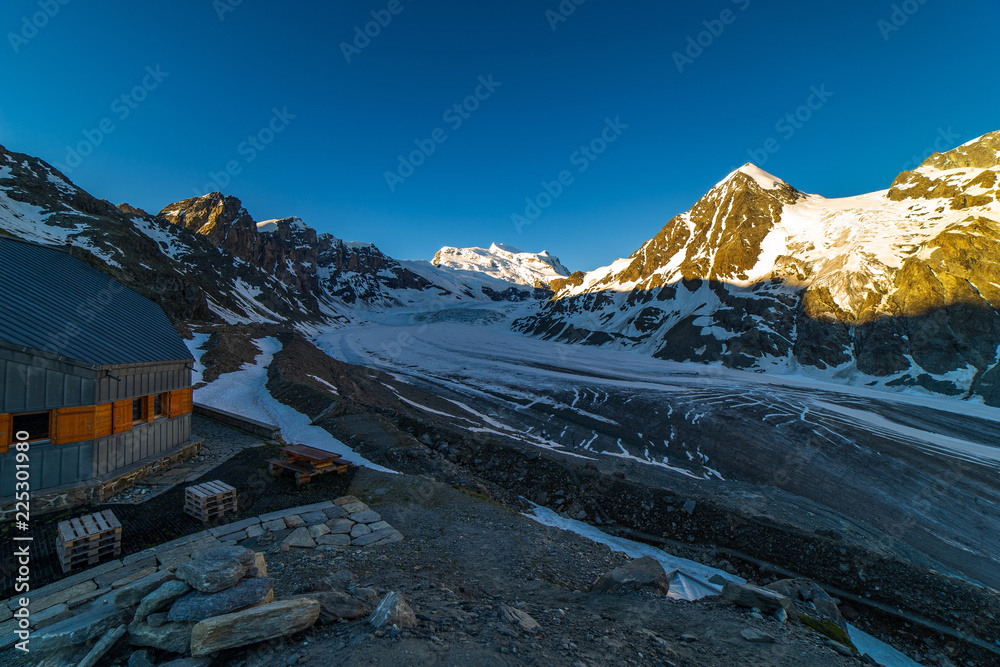 Obraz premium Scenic view of beautiful landscape of Swiss Alps with a majestic Glacier de Corbassiere in a view, Switzerland. Clear sky sunrise in Valais Alps (Pennine Alps), Switzerland in a early morning light.