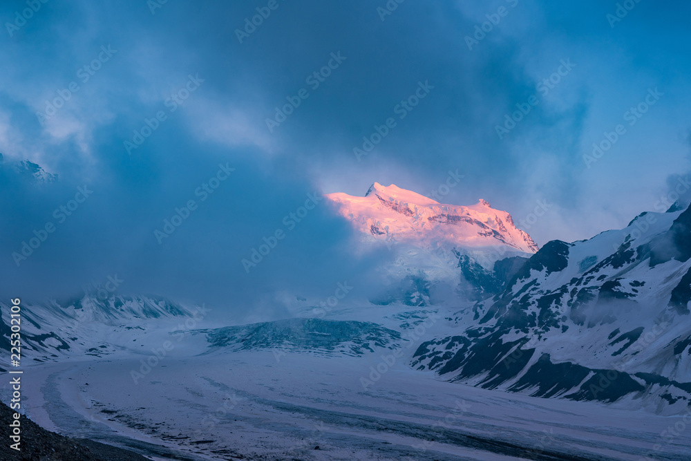 Obraz premium Glacier de Corbassiere, Switzerland. Dramatic sunset scene in high mountains. Clouds covering high peaks of Valais Alps (Pennine Alps), Switzerland in a evening light.